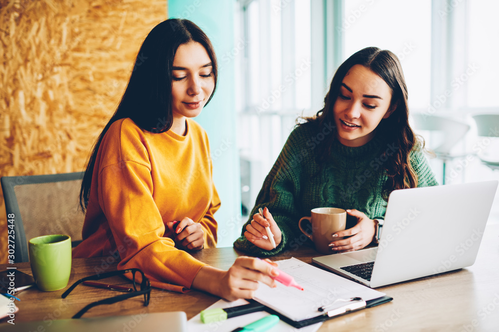 Poster businesswomen checking work's plan for developing startup project sitting in studio at desktop with 