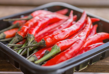 Spicy hot red peppers in black plastic plate - 302725403