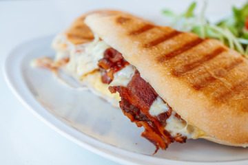 Close up of sandwich toast grilled with bacon and cheese on white plate