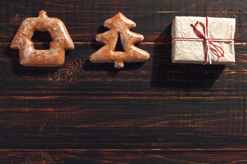 Christmas gingerbread cookies in the shape of a Christmas tree and craft gifts on a wooden background.