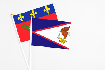 American Samoa and Guadeloupe stick flags on white background. High quality fabric, miniature national flag. Peaceful global concept.White floor for copy space.