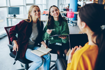 Smiling caucasian girl listening to female coach explaining information during training workshop, female crew of designers talking to each other and share creative ideas on meeting in coworking office