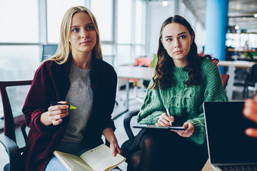 Serious female students listening to coach explanation making notes during training, cropped image of caucasian women concentrated during meeting with coach planning strategy for work cooperation
