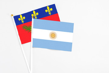 Argentina and Guadeloupe stick flags on white background. High quality fabric, miniature national flag. Peaceful global concept.White floor for copy space.