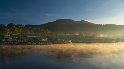 Morning view of Ban Rak Thai Village,Chinese Yunnan village on lakeside with green hill,sunlight,fog and clear sky background, Ban Rak Thai,Mae Hong Son, northern of Thailand.