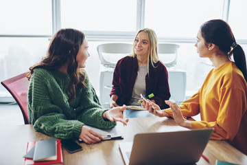 Positive crew of female designers having conversation during cooperation process in coworking...