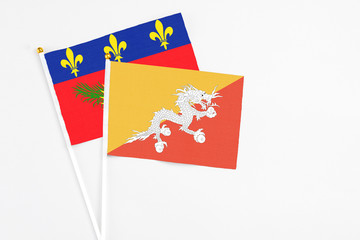 Bhutan and Guadeloupe stick flags on white background. High quality fabric, miniature national flag. Peaceful global concept.White floor for copy space.