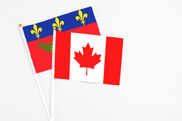 Canada and Guadeloupe stick flags on white background. High quality fabric, miniature national flag. Peaceful global concept.White floor for copy space.