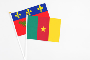 Cameroon and Guadeloupe stick flags on white background. High quality fabric, miniature national flag. Peaceful global concept.White floor for copy space.