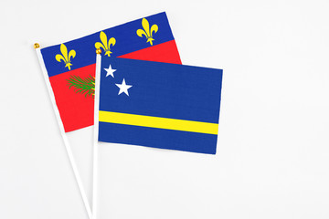 Curacao and Guadeloupe stick flags on white background. High quality fabric, miniature national flag. Peaceful global concept.White floor for copy space.