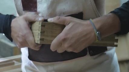 a joiner in an apron cuts a dovetail joint