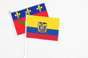 Ecuador and Guadeloupe stick flags on white background. High quality fabric, miniature national flag. Peaceful global concept.White floor for copy space.