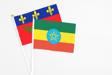 Ethiopia and Guadeloupe stick flags on white background. High quality fabric, miniature national flag. Peaceful global concept.White floor for copy space.