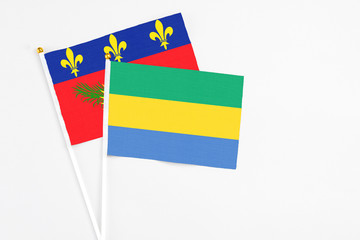 Gabon and Guadeloupe stick flags on white background. High quality fabric, miniature national flag. Peaceful global concept.White floor for copy space.