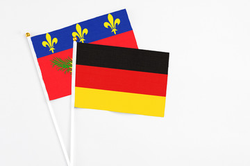 Germany and Guadeloupe stick flags on white background. High quality fabric, miniature national flag. Peaceful global concept.White floor for copy space.