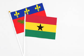 Ghana and Guadeloupe stick flags on white background. High quality fabric, miniature national flag. Peaceful global concept.White floor for copy space.