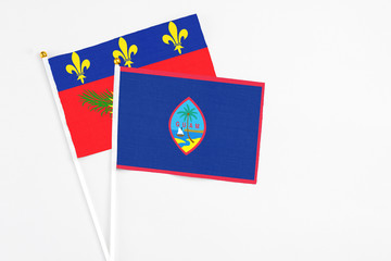Guam and Guadeloupe stick flags on white background. High quality fabric, miniature national flag. Peaceful global concept.White floor for copy space.