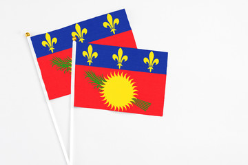 Guadeloupe and Guadeloupe stick flags on white background. High quality fabric, miniature national flag. Peaceful global concept.White floor for copy space.