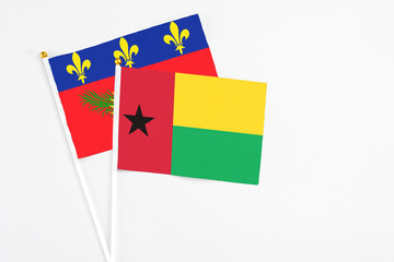 Guinea Bissau and Guadeloupe stick flags on white background. High quality fabric, miniature national flag. Peaceful global concept.White floor for copy space.