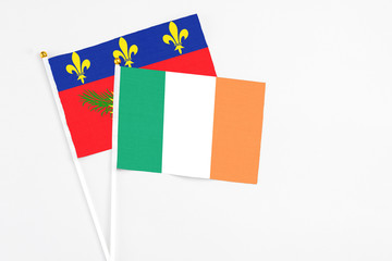 Ireland and Guadeloupe stick flags on white background. High quality fabric, miniature national flag. Peaceful global concept.White floor for copy space.