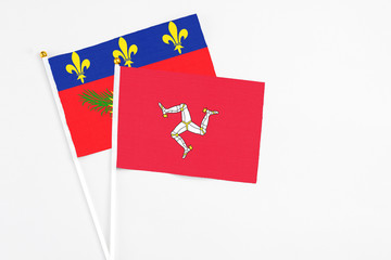 Isle Of Man and Guadeloupe stick flags on white background. High quality fabric, miniature national flag. Peaceful global concept.White floor for copy space.