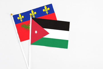Jordan and Guadeloupe stick flags on white background. High quality fabric, miniature national flag. Peaceful global concept.White floor for copy space.