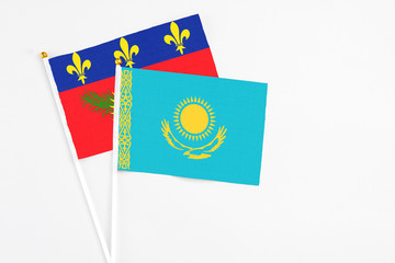 Kazakhstan and Guadeloupe stick flags on white background. High quality fabric, miniature national flag. Peaceful global concept.White floor for copy space.