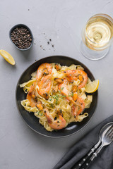 Pasta reginelle with seafood, shrimps, mussels black plate on gray stone table, top view. Traditional dish in Italian restaurant.