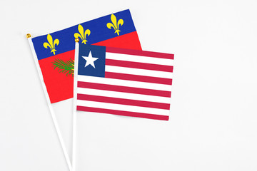 Liberia and Guadeloupe stick flags on white background. High quality fabric, miniature national flag. Peaceful global concept.White floor for copy space.