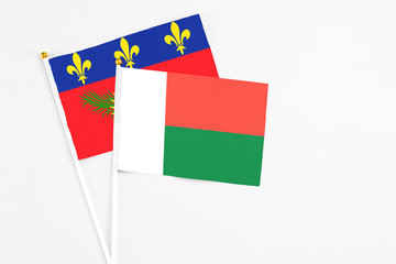 Madagascar and Guadeloupe stick flags on white background. High quality fabric, miniature national flag. Peaceful global concept.White floor for copy space.