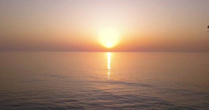 Paragliding into the sunset. Low aerial footage footage of Amazing sunset over sea. Summer sunset seascape.