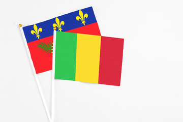 Mali and Guadeloupe stick flags on white background. High quality fabric, miniature national flag. Peaceful global concept.White floor for copy space.