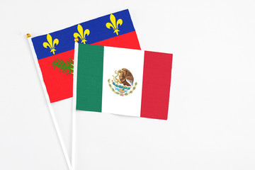 Mexico and Guadeloupe stick flags on white background. High quality fabric, miniature national flag. Peaceful global concept.White floor for copy space.