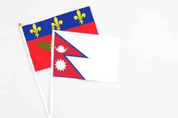 Nepal and Guadeloupe stick flags on white background. High quality fabric, miniature national flag. Peaceful global concept.White floor for copy space.