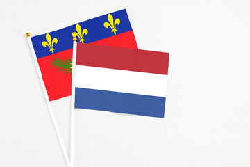 Netherlands and Guadeloupe stick flags on white background. High quality fabric, miniature national flag. Peaceful global concept.White floor for copy space.