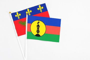 New Caledonia and Guadeloupe stick flags on white background. High quality fabric, miniature national flag. Peaceful global concept.White floor for copy space.