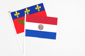Paraguay and Guadeloupe stick flags on white background. High quality fabric, miniature national flag. Peaceful global concept.White floor for copy space.