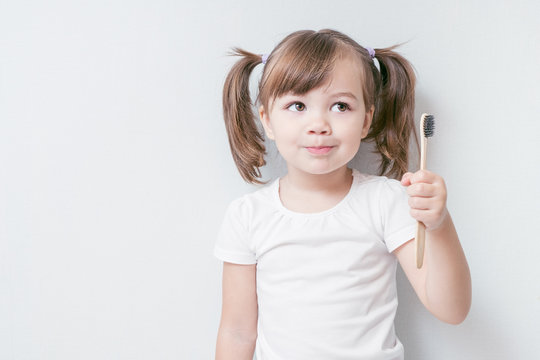 child girl brushes her teeth with a bamboo toothbrush. concept: environmental care, zero waste, ecology