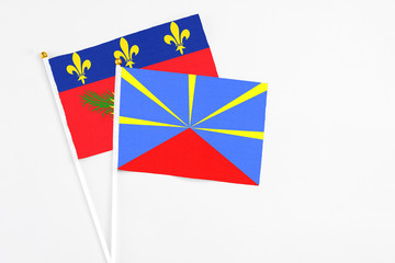 Reunion and Guadeloupe stick flags on white background. High quality fabric, miniature national flag. Peaceful global concept.White floor for copy space.