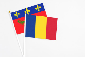 Romania and Guadeloupe stick flags on white background. High quality fabric, miniature national flag. Peaceful global concept.White floor for copy space.