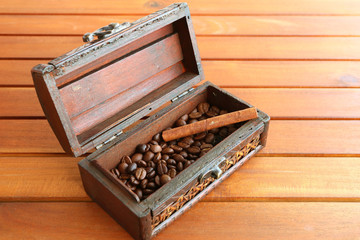Roasted coffee beans with cinnamon stick in a wooden box isolated on wooden table