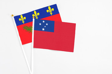 Samoa and Guadeloupe stick flags on white background. High quality fabric, miniature national flag. Peaceful global concept.White floor for copy space.