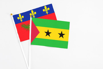 Sao Tome And Principe and Guadeloupe stick flags on white background. High quality fabric, miniature national flag. Peaceful global concept.White floor for copy space.