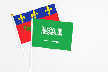 Saudi Arabia and Guadeloupe stick flags on white background. High quality fabric, miniature national flag. Peaceful global concept.White floor for copy space.