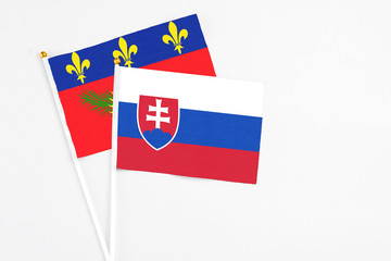Slovakia and Guadeloupe stick flags on white background. High quality fabric, miniature national flag. Peaceful global concept.White floor for copy space.