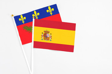 Obraz premium Spain and Guadeloupe stick flags on white background. High quality fabric, miniature national flag. Peaceful global concept.White floor for copy space.
