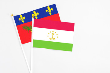 Tajikistan and Guadeloupe stick flags on white background. High quality fabric, miniature national flag. Peaceful global concept.White floor for copy space.