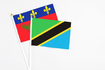 Tanzania and Guadeloupe stick flags on white background. High quality fabric, miniature national flag. Peaceful global concept.White floor for copy space.