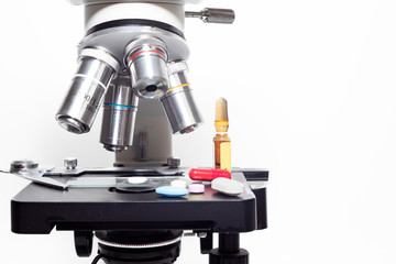 Optical microscope with some vitamin pills supplements and medicines, as well as a vial with drugs