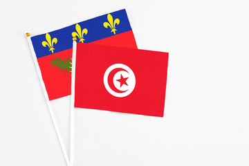 Tunisia and Guadeloupe stick flags on white background. High quality fabric, miniature national flag. Peaceful global concept.White floor for copy space.